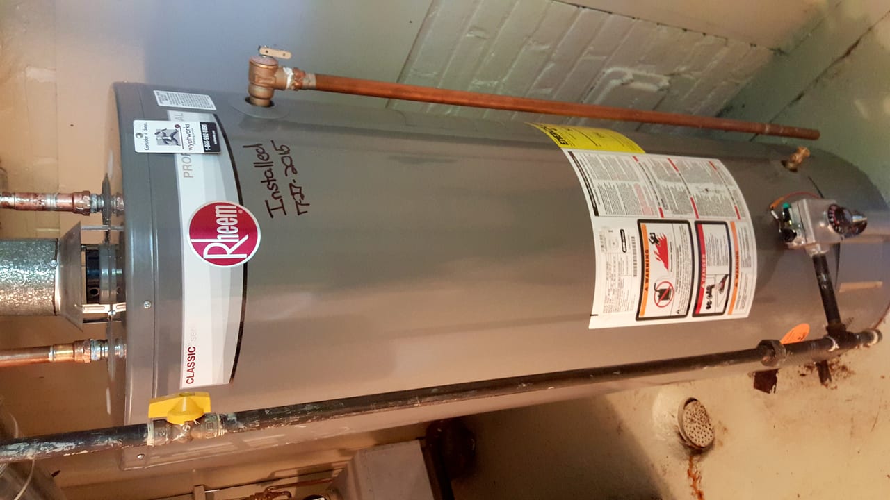 Residential tank water heater with visible plumbing connections