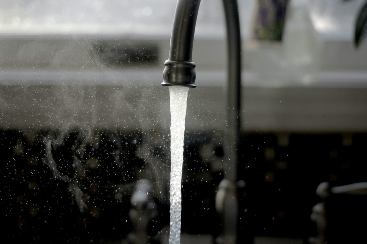 Running water from a chrome kitchen faucet over a sink