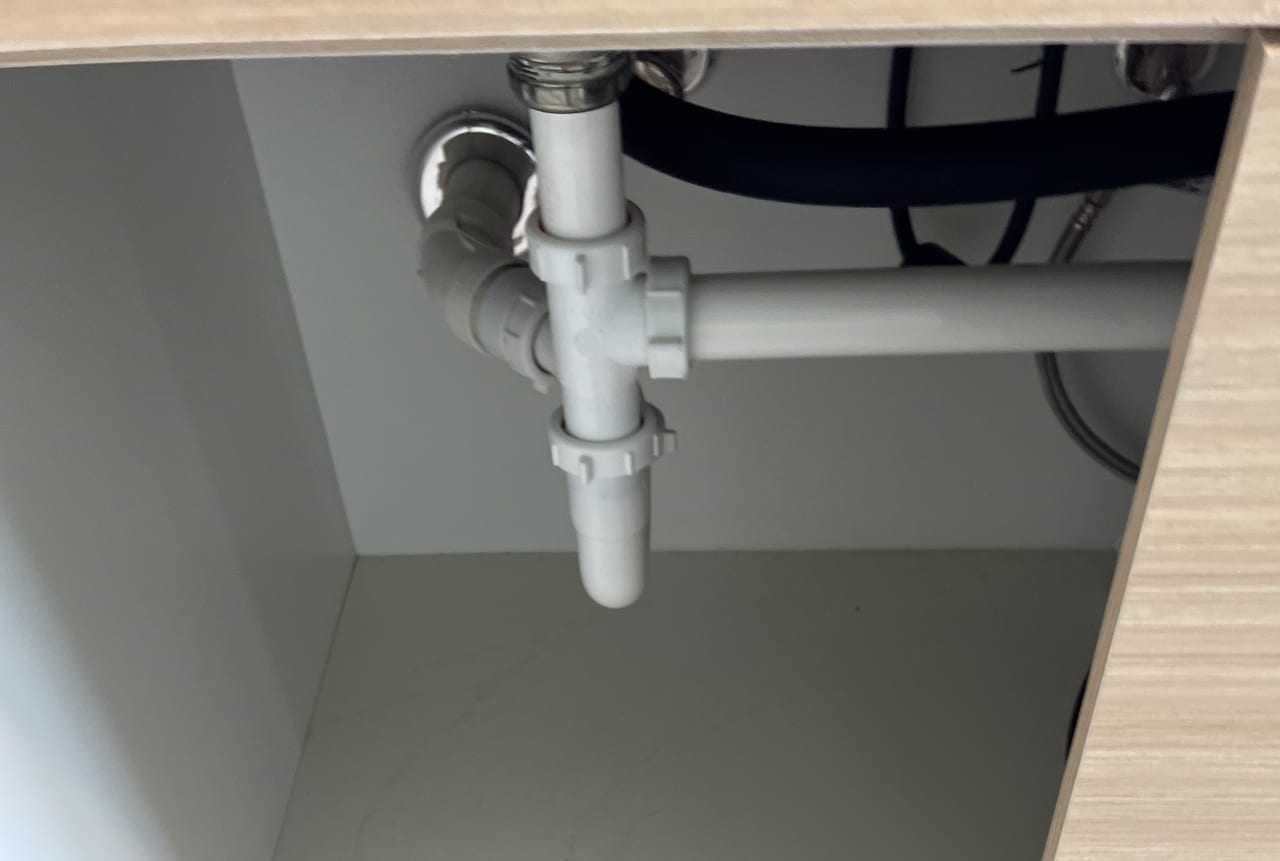 Accessible PVC drain pipes and connections beneath a sink